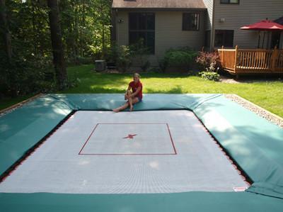 What are the health benefits of jumping on a trampoline? Well, it's what Olympians use to train. A young gymnast sits on a green pad surrounding her in-ground trampoline.