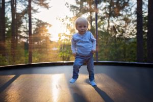 MaxAir's tips on buying a trampoline. A young child bounces on a trampoline at dusk.