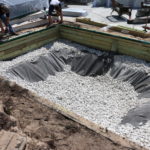 A pit set foundation for an in-ground trampoline. This provides ample space for bouncing and allows drainage.
