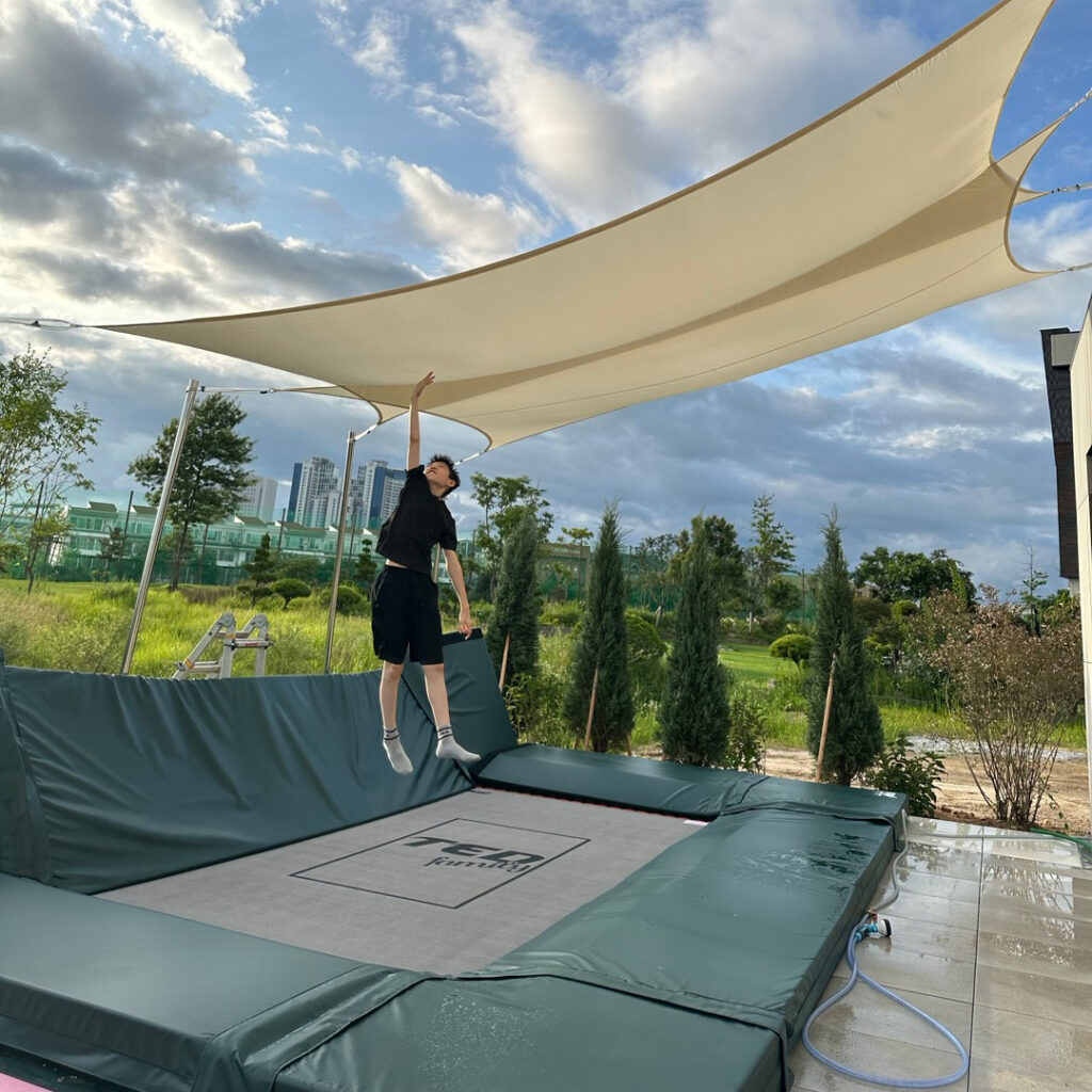 A boy jumping on an in-ground trampoline with a canopy above.