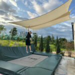 A boy jumping on an in-ground trampoline with a canopy above.