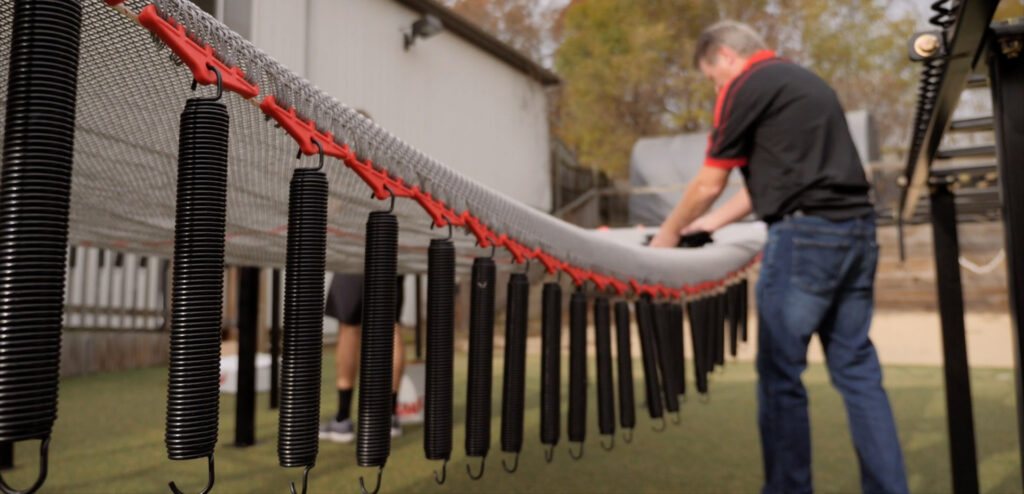 Trampoline springs hung from a trampoline bed bounce mat ready to be attached to the trampoline frame.