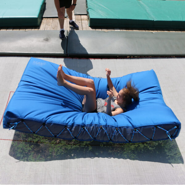 A young woman lands on a crash pad pitch mat on a trampoline by MaxAir Trampolines.